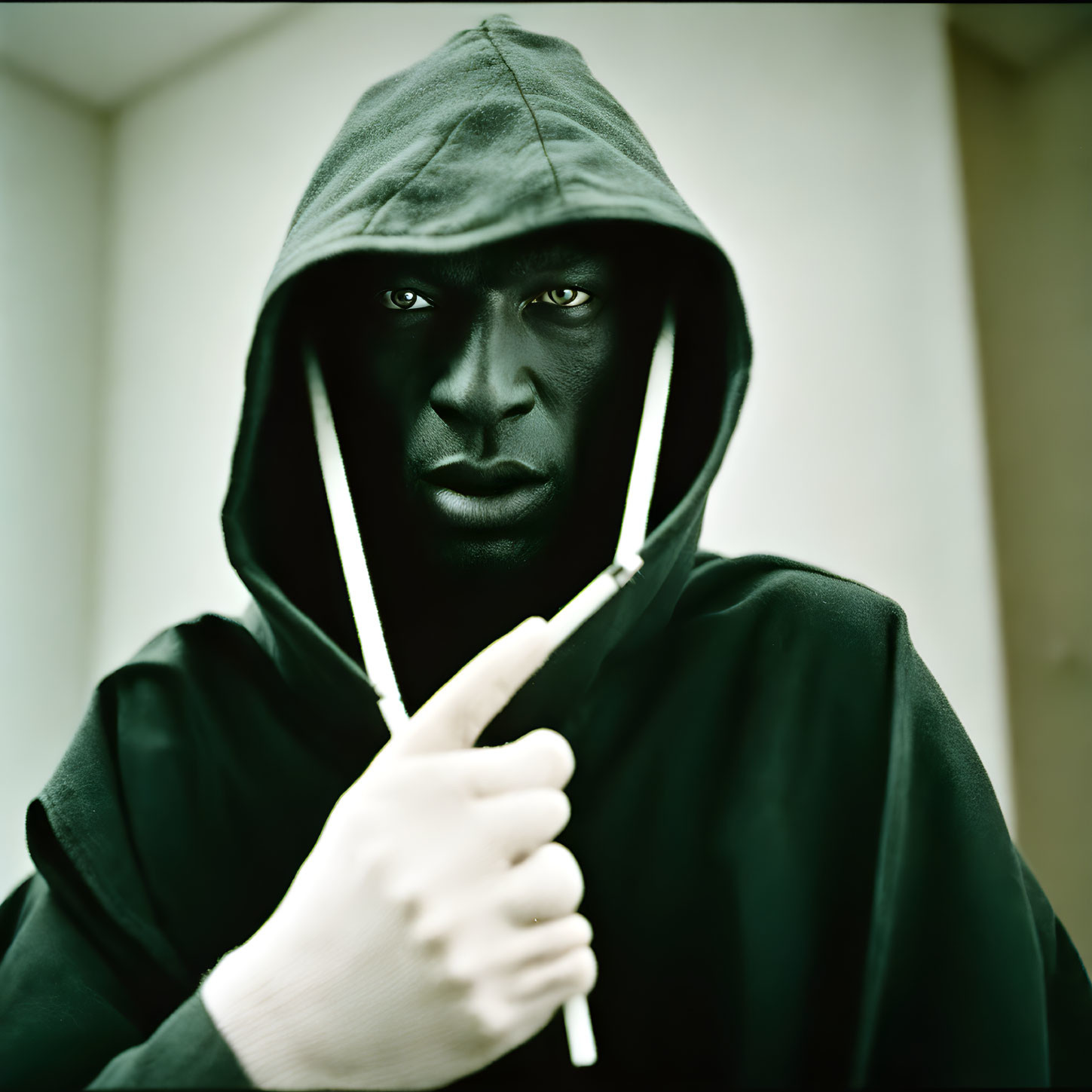 Intense individual in hooded sweatshirt with drawn hood and drawstrings
