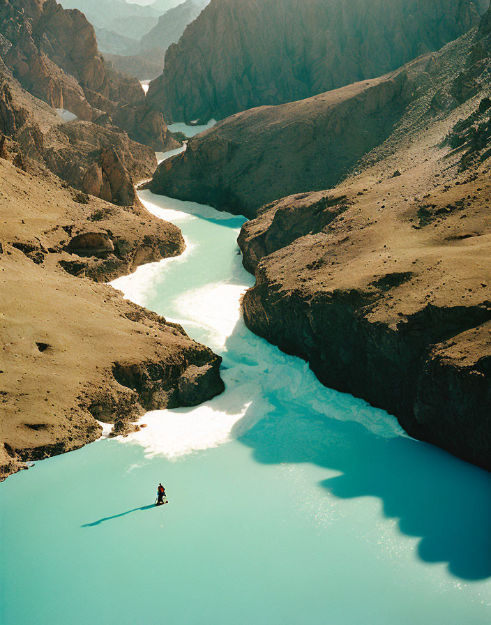 Kayaker navigating turquoise river in mountainous landscape