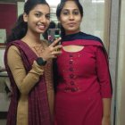 Two Women in Burgundy Dresses with Silver Accessories Amongst White Flowers