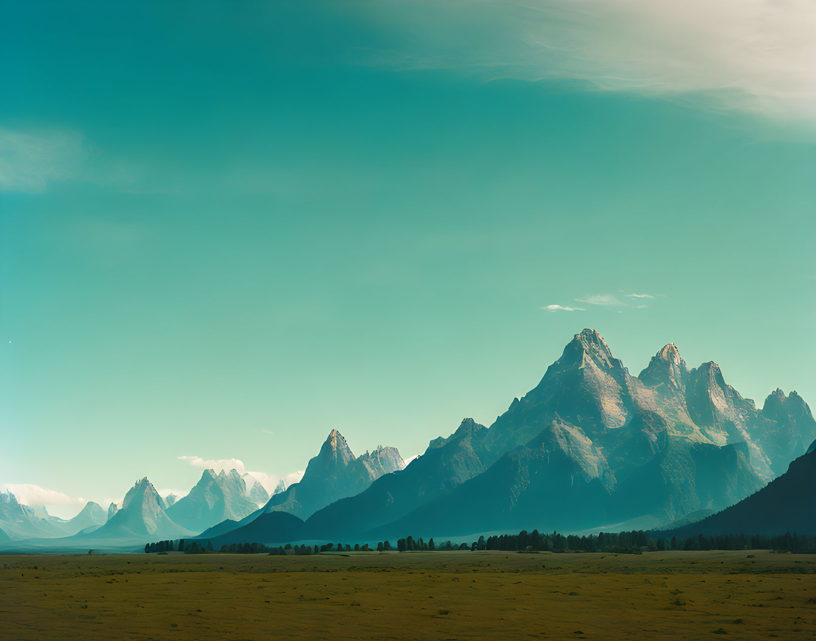 Jagged mountains and open field under clear blue sky