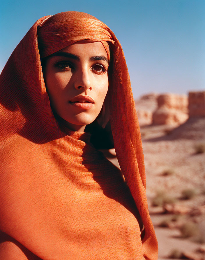 Woman wearing vibrant orange scarf in arid rocky terrain