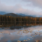 Scenic autumn lake with floating leaves, forest, and mountains