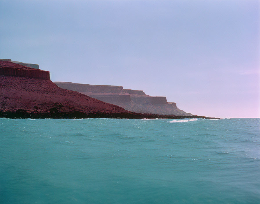 Stratified cliffs by calm blue sea with geological layers