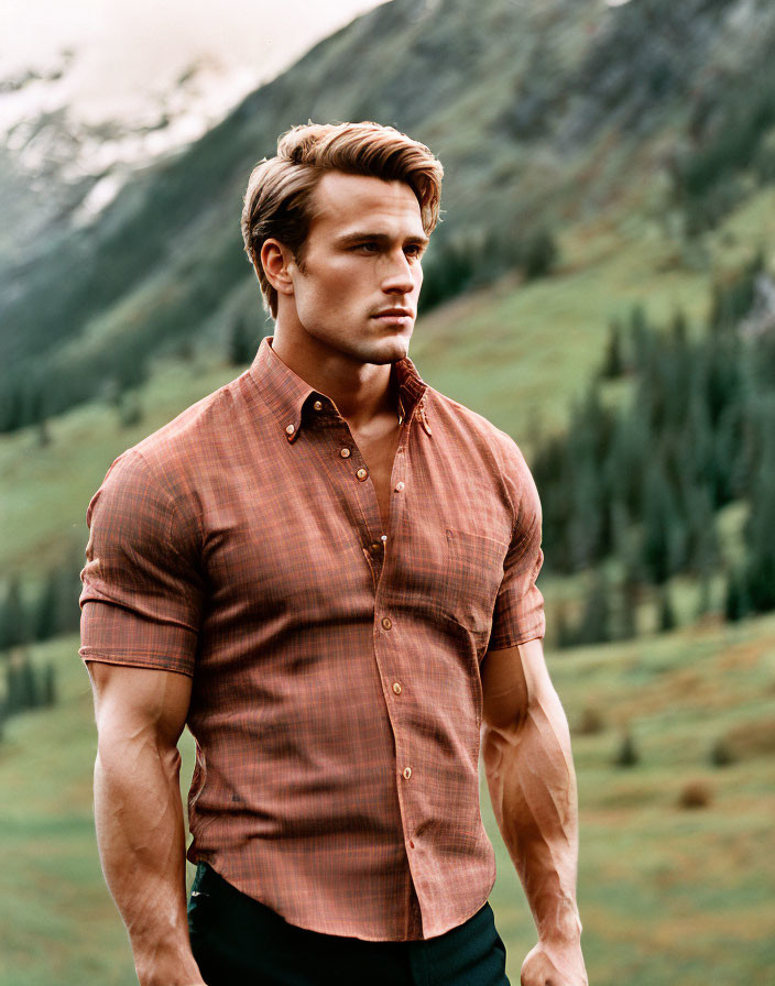 Man in Brown Shirt Stands Outdoors with Mountain Landscape