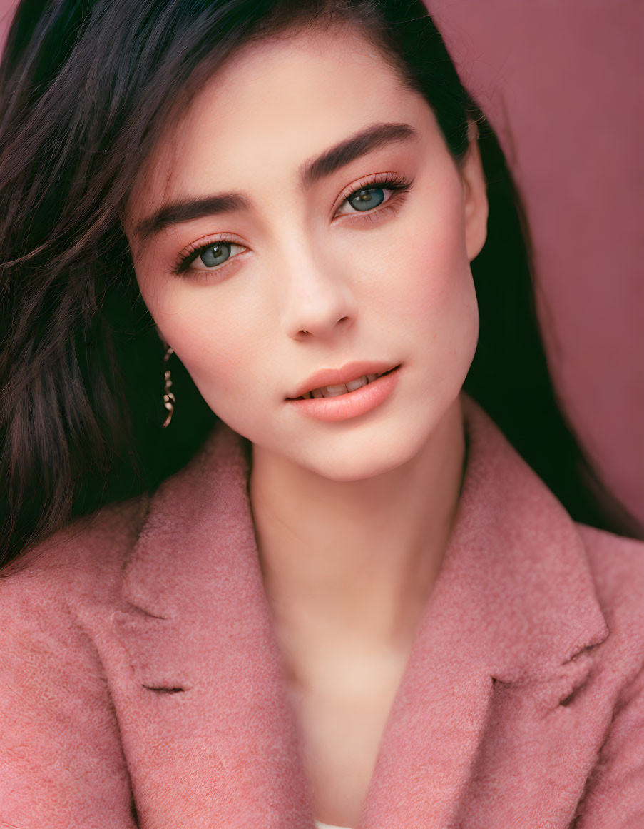 Portrait of Woman with Dark Hair and Hazel Eyes in Pink Coat on Pink Background