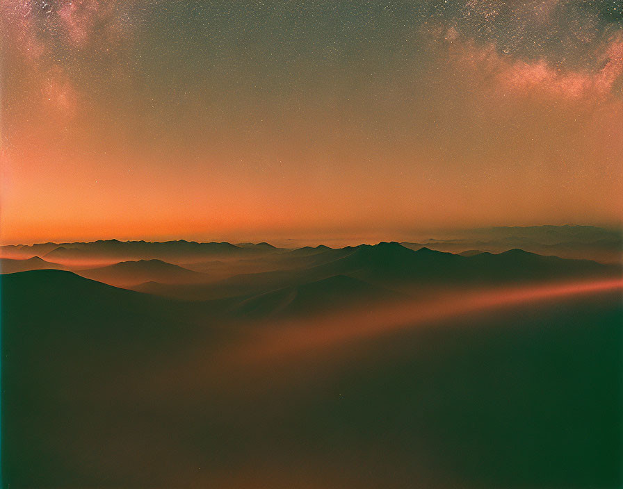 Twilight landscape with layered mountains and transitioning sky.