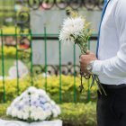 Bride in white gown with bouquet meets groom in black suit in lush garden