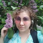 Portrait of young person with flowers in hair and rose, surrounded by green foliage