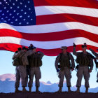 Soldiers in Camo Gear Under Large American Flag at Twilight