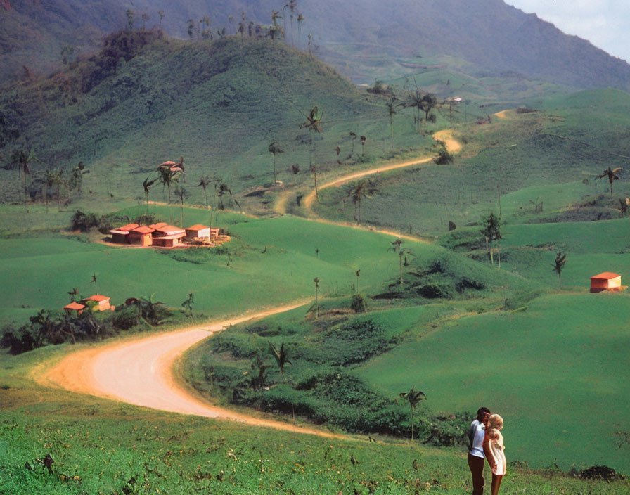 Rural landscape with two people, dirt road, and houses