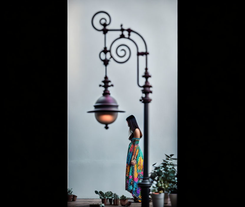 Blurred figure in colorful outfit near ornate street lamp