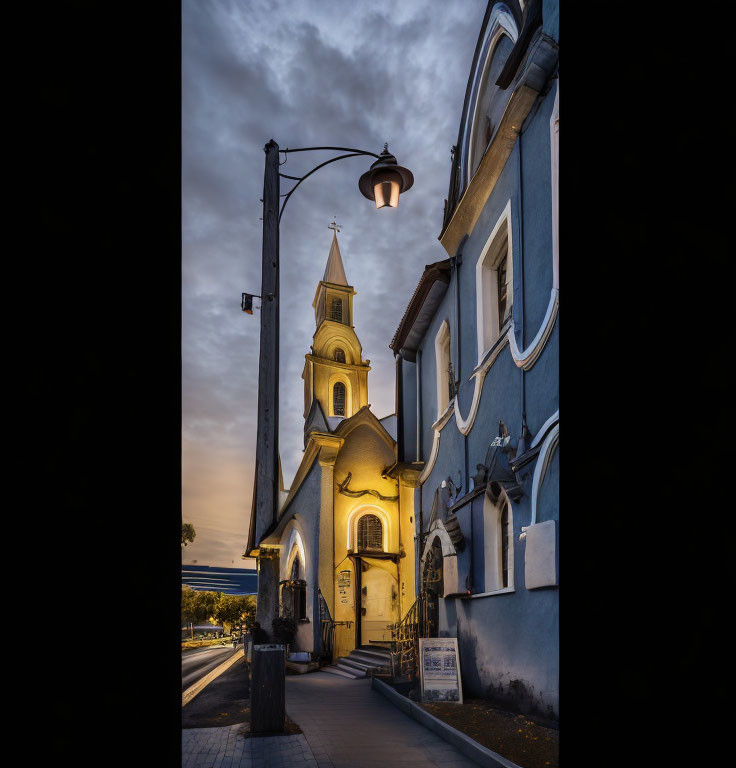 Dusk scene of illuminated church and street lamp with contrasting sky tones