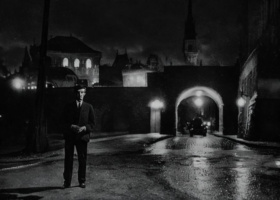 Monochrome photo of man on rainy city street at night