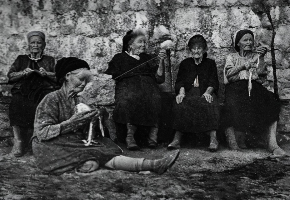 Elderly women in traditional attire knitting and holding walking sticks.