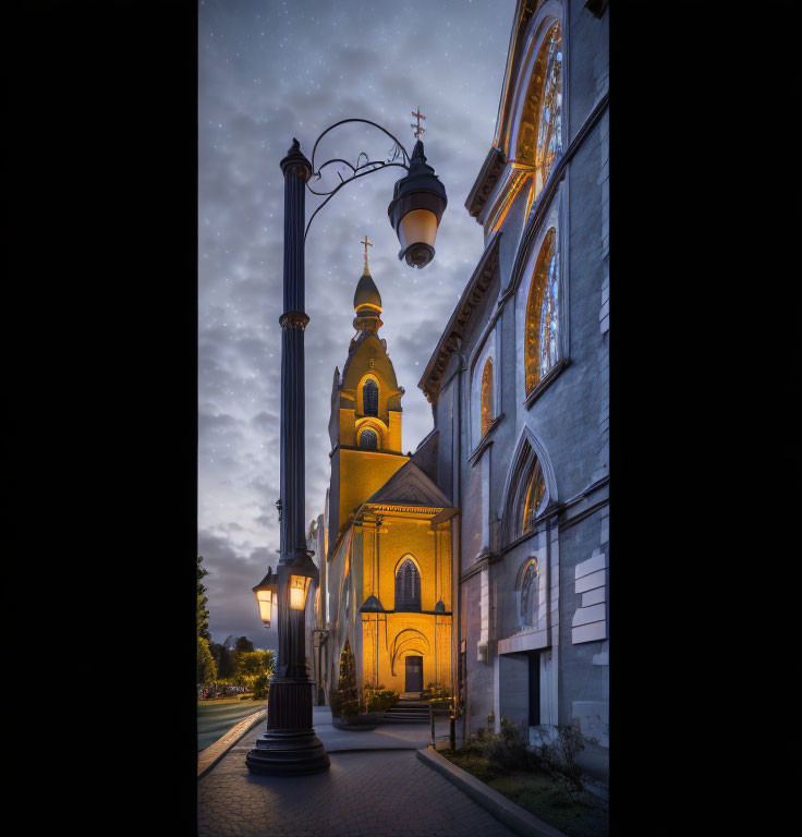 Illuminated church with towering spire under starry twilight sky