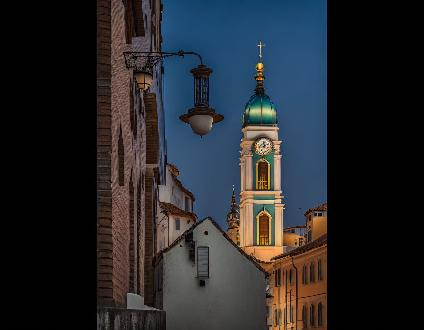 Twilight scene: Elegant clock tower with gold and green dome amidst old European-style buildings under deep blue