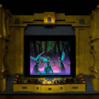 Opulent theater stage with golden statues and royal play scene under dramatic blue lighting