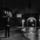 Monochrome photo of man on rainy city street at night