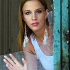 Serene woman looking through misted window with feather earrings