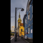 Rainy evening scene: street with glowing lamps, elegant church with gold-trimmed entrance and cross