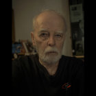 Man with Shoulder-Length Wavy Hair and Beard in Dark Robe Portrait