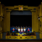 Historical costume performers on illuminated stage with candles and starry backdrop