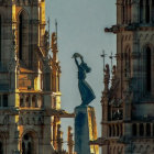 Robed Figure Statue with Crown, Scepter, and Gothic Towers on Blue Sky