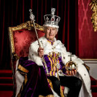 Regal man in crown and sash on throne with scepter in red and gold setting