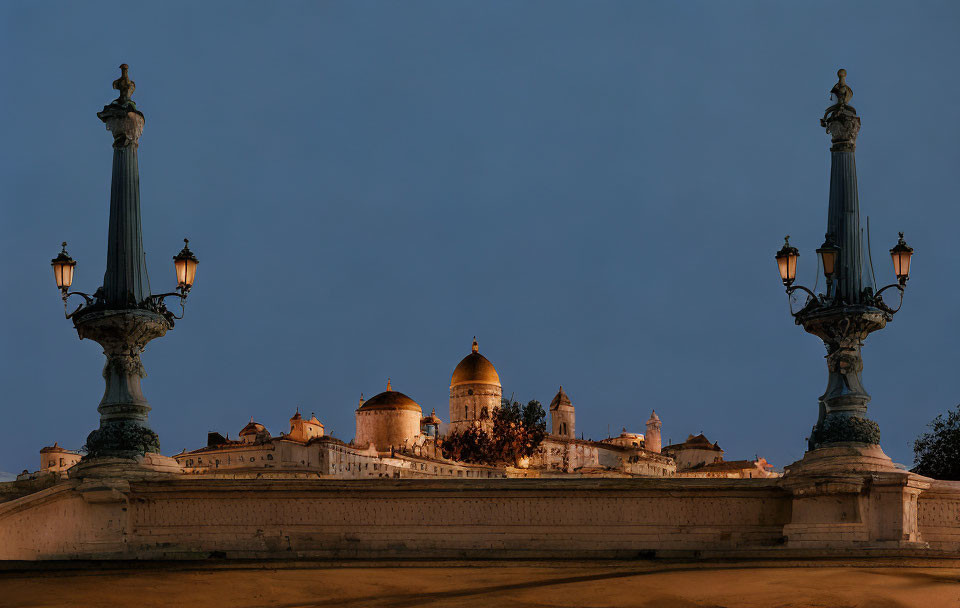 Historic cityscape with illuminated street lamps and dome architecture at twilight.