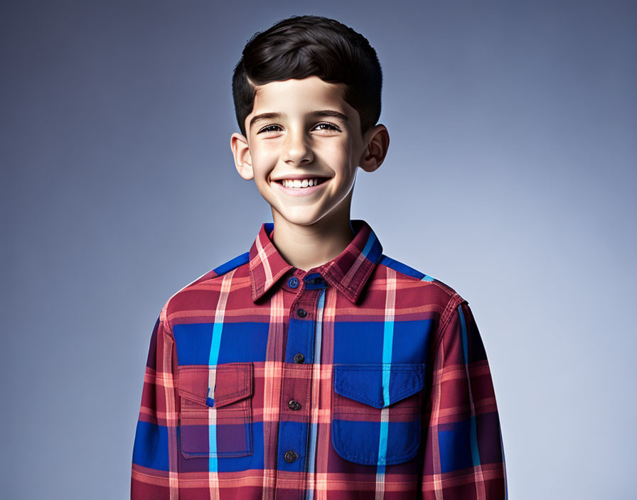 Young boy in red and blue plaid shirt on gradient blue backdrop