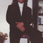 Confident man with flowing hair in pinstriped suit against geometric background