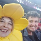 Smiling people in yellow sports fan gear at stadium