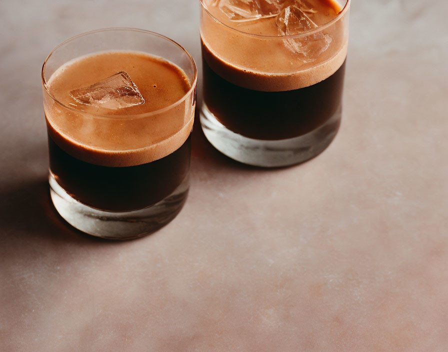 Iced black coffee with frothy layer on textured surface