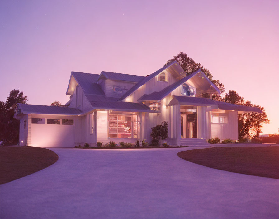 Contemporary house with interior lights and driveway under twilight sky