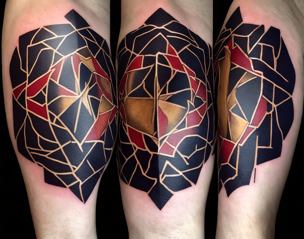 Geometric tattoo on arm with abstract patterns in black, gold, and red colors