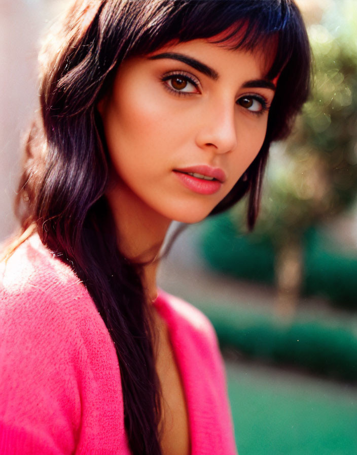 Woman with Long Dark Hair in Pink Top Poses in Sunlit Setting