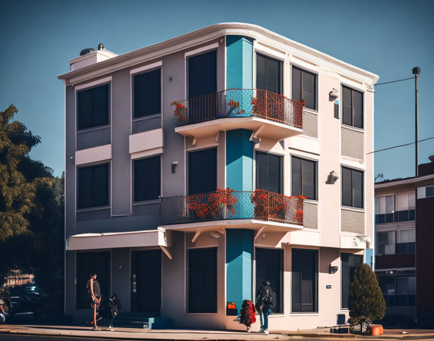 Three-story building with blue accents, red flower balconies, person walking, and motorcycle.