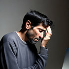 Stressed man holding head in front of laptop on desk