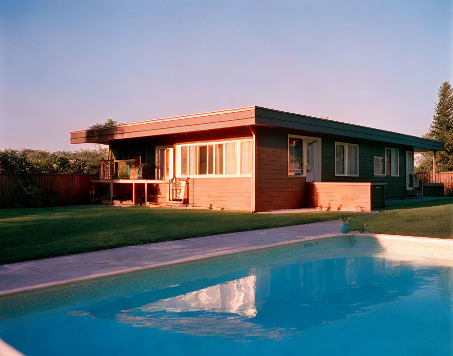 Suburban house with red and beige façade, large windows, porch, and pool.