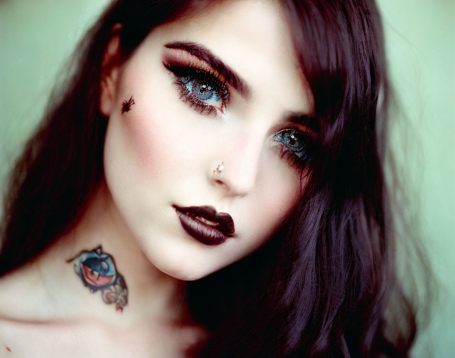 Portrait of woman with striking makeup, nose ring, and collarbone tattoo