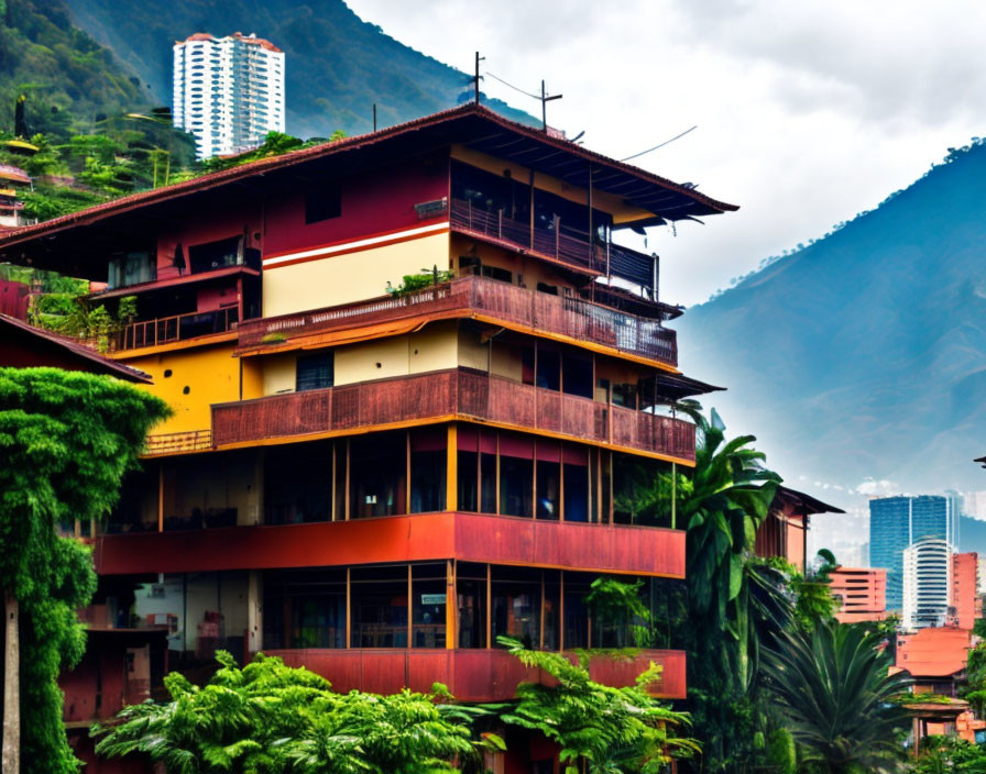 Vibrant red and yellow building with balconies, set amidst greenery and mountains