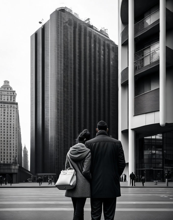 Two individuals pondering contrasting urban skyscrapers