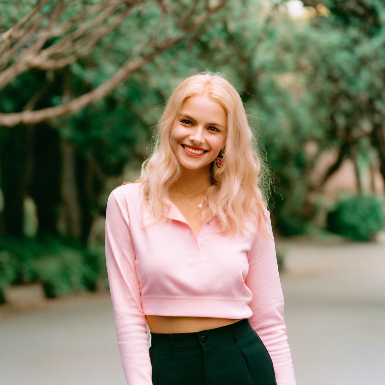 Blonde Woman Smiling in Pink Top and Black Trousers in Park Setting