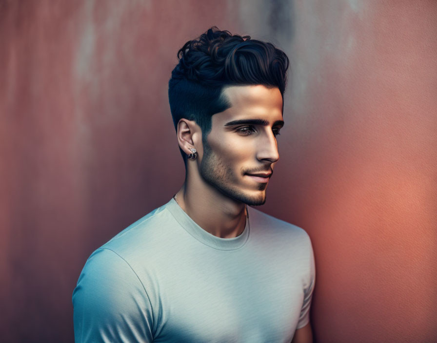 Man with styled hair and stubble in fitted t-shirt on orange backdrop