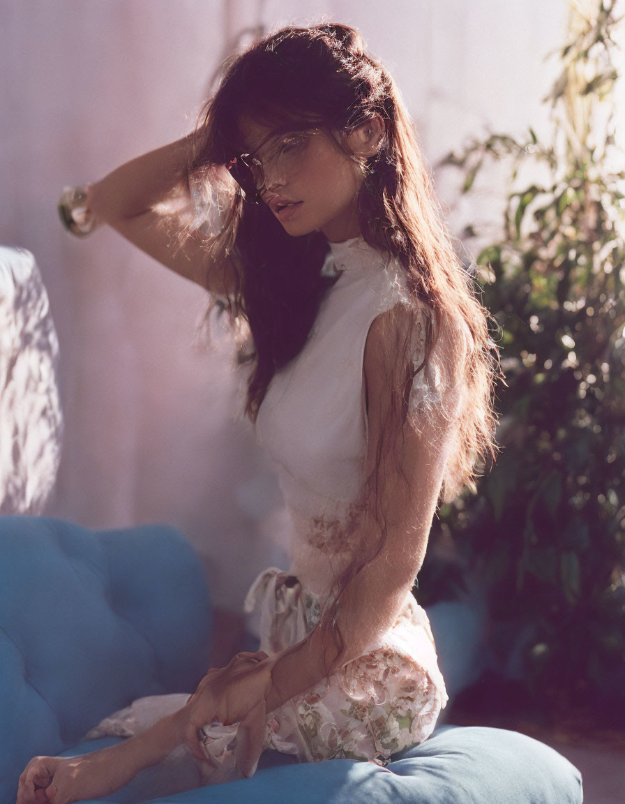 Woman in Floral Dress Sitting on Blue Couch in Sunlight