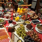 Luxurious dining table set with ornate glassware, gold accents, fruits, and sweets