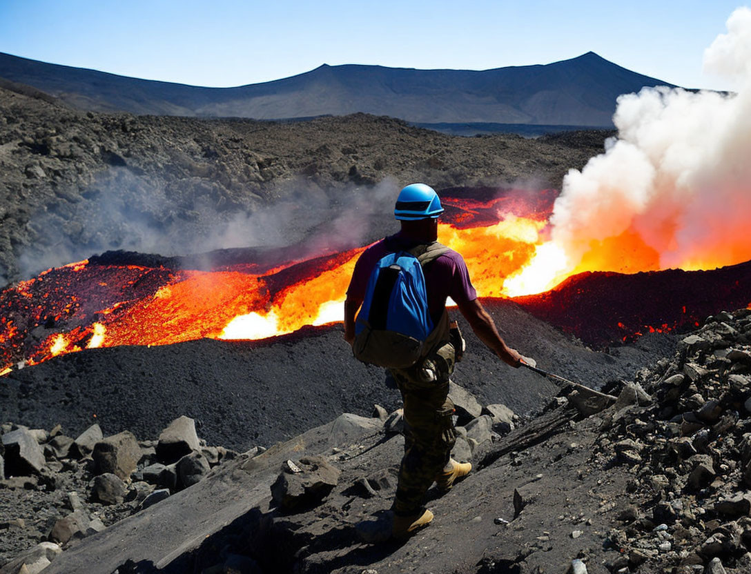 Person near lava flow wearing helmet observes volcanic eruption