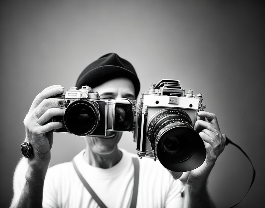 Vintage Cameras Held by Person Against Grey Background