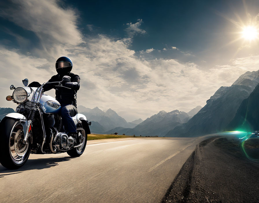 Person in black outfit rides motorcycle on mountain road under sunny sky