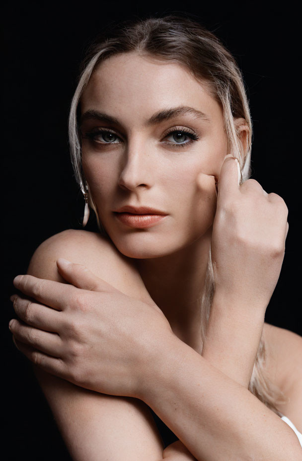 Blonde woman with striking eyes, elegant pose on black background